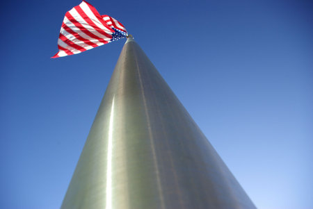 A unique view of a large American flag flying from the top of an aluminim flagpole.