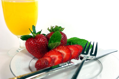 Sliced strawberries and orange juice on a white backgroundの写真素材