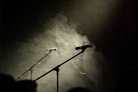 Two microphones standing in a cloud of smoke waiting for the band to arrive and start playing.の写真素材