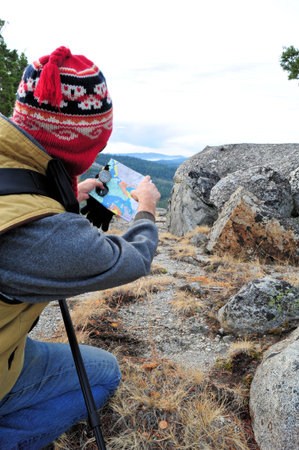 A single male day hiker checking map with compass