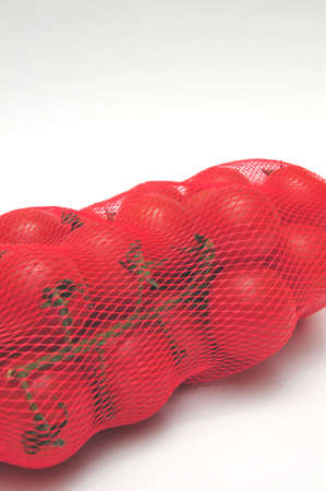 Small tomatos in a plastic mesh bagの写真素材