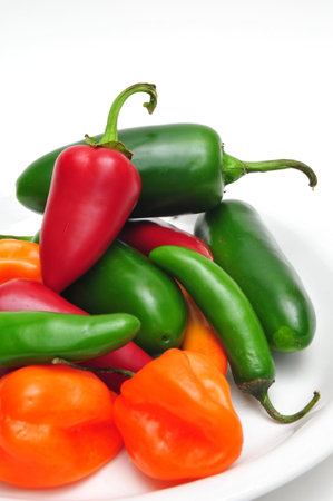 Jalaneno, Serrano and Habanero chilis in a white bowl on a light background
