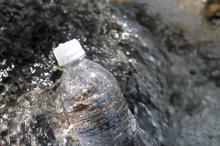 Single clear container of spring water in chilling in a small stream