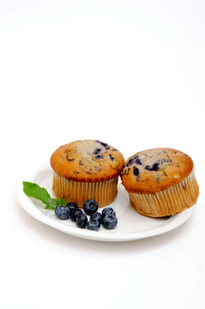 Blueberry muffins on a white plate with fresh berries on the sideの写真素材