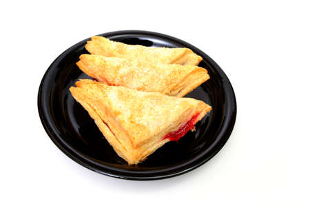 Three Cherry turnovers on a black plate isolated on a white backgroundの写真素材