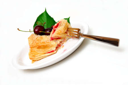 Cherry filled flakey turnover on a white plate with fresh cherries on the side.の写真素材