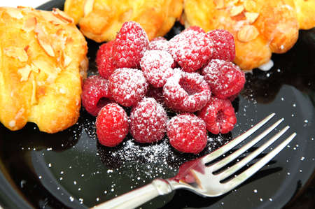 Bearclaw pastries with fresh picked Raspberries on a black plate with a fork in the foregroundの写真素材