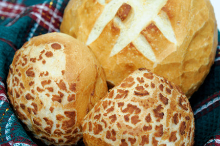 Loaf of sourdough bread and 2 rolls in a basket lined with a green cloth