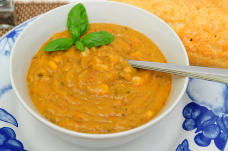 Hot vegetable soup with a sprig of basil served in a white bowlの写真素材