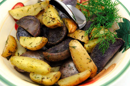 Purple and yellow new potatoes roasted in olive oil and spices including Dill weedの写真素材