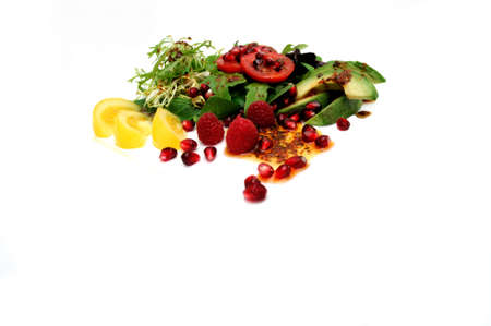 Salad ingredients isolated on a white background with red roma and yellow heirloom tomatoes, avocado slices, spinach leaf, pomegranate seeds, Raspberries topped with Olive oil and Raspberry vinaigrette dressingの写真素材
