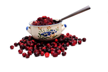 A side view of a bowl of fresh cranberry sauce with raw cranberries under the bowl の写真素材
