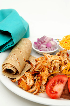 Shredded grilled spiced chicken on a white plate with fresh tortilla's, refried beans with sides of red onion, cheddar cheese and hot sauce.の写真素材