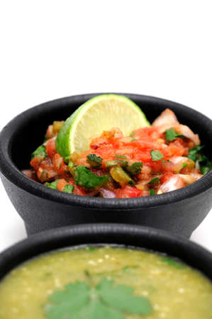 Bowls of spicy homemade salsa topped with fresh lime both tomato and salsa verde are includedの写真素材