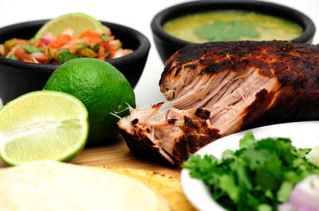 Pork roast cooked to make Mexican carnitas with fresh tortilla's' chunky tomato salsa and salsa verde and sliced limesの写真素材