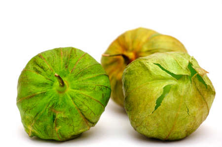 Three ripe tomatillos on a light colored background with various shades of green and brown on the husk ready to be peeled and used as the main ingredient for Mexican salsa verde.の写真素材