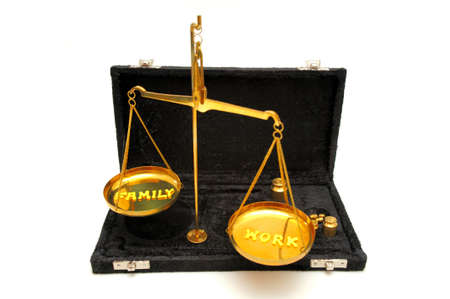 Conceptual image  of keeping the job and family in balance in a busy and stressful world using a brass  balance scale with yellow letters to spell out the conceptの写真素材