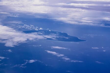 View from an airplane out of the window flying above the ocean with blue sky and clouds. Bird eyes view of the planet..の写真素材