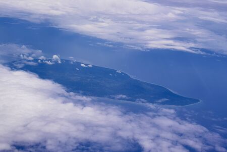 View from an airplane out of the window flying above the ocean with blue sky and clouds. Bird eyes view of the planet..の写真素材