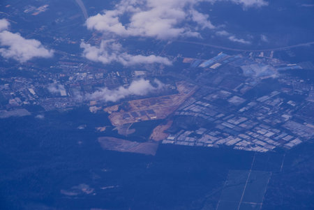 View from an airplane out of the window flying above the ocean with blue sky and clouds. Bird eyes...