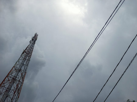 A Communication Tower And Power Cables With A Cloudy Sky Background