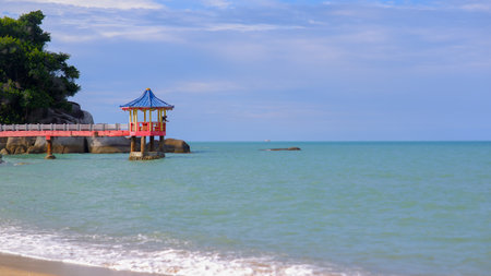 A Colorful Pagoda-style Gazebo Stands On Stilts In The Middle Of The Calm Sea, Surrounded By A Bright Blue Skyの写真素材