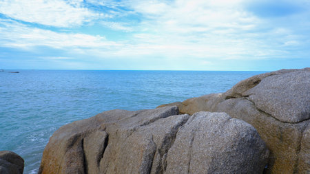 Close-up Of A Small Rock Appearing In The Middle Of A Calm Sea. Gentle Waves Create Ripples Around...