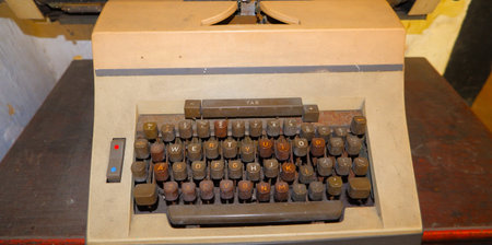 An Old Typewriter With A Cream Colored Body And A Brown Keyboard. The Keys Are Worn And The Paint Is...