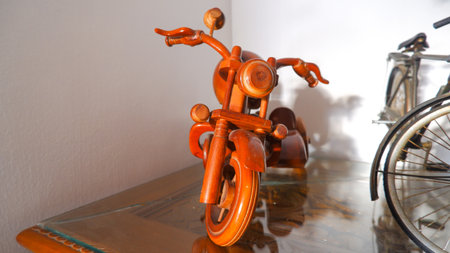 A Miniature Toy Motorbike Made Of Handmade Wood, Placed On A Glass Tableの写真素材