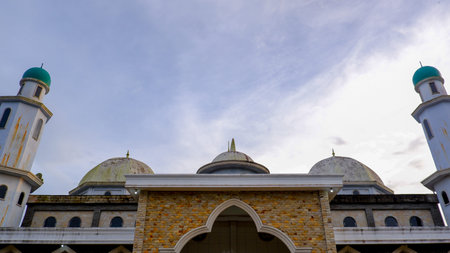 A low-angle, eye-level shot that captures the grandeur of the mosque's exterior against a partly...