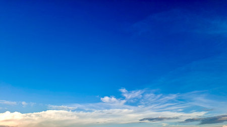 A bright, deep blue sky dominates the top of the frame, transitioning to a softer, lighter blue toward the horizon with wispy cirrus clouds.の写真素材