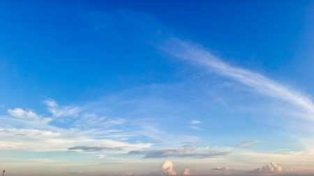 A stunning expanse of bright blue sky dominates the frame, transitioning subtly to softer, lighter hues towards the thin cloud-covered horizon.の写真素材