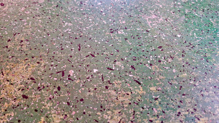 Textured close-up of a rough surface, possibly terrazzo or a similar composite material. The base...