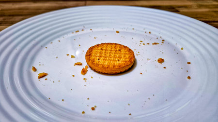 A close-up of a single golden cake placed in the center of a white ceramic plate, surrounded by...