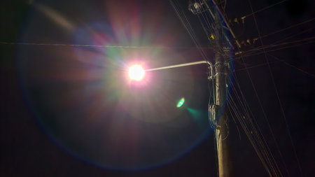 A clear nighttime photo of a street light mounted on a utility pole, illuminating the dark sky with intense brightness.の写真素材