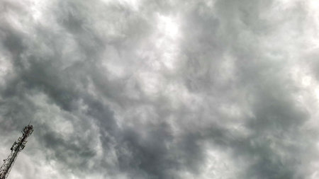 Dark gray storm clouds cover the sky with a communication tower visible in the corner. The thick cloud formation creates a dramatic and intense atmosphere.の写真素材