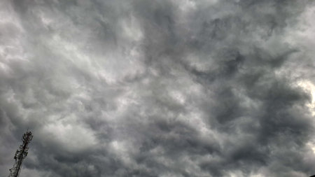 A powerful and dramatic photo of a stormy sky filled with thick, dark clouds, contrasted with a lone...