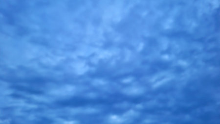 Dramatic cloudy blue sky abstract background at dusk. Soft cloud formations spread across the sky,...
