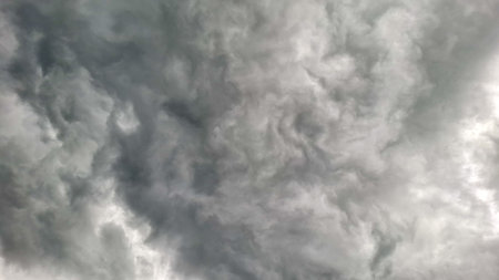 A dramatic, gloomy sky filled with thick, swirling dark storm clouds, depicting an intense weather...