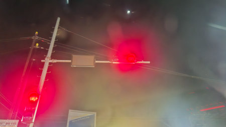 A dynamic night shot that captures the bright light of multiple red traffic lights amidst city fog...