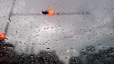 A close-up shot of a car windshield covered in countless raindrops, creating a textured, blurry look at the outside world.の写真素材