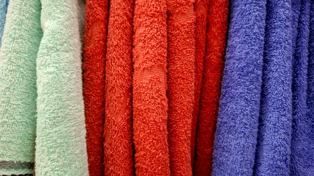 Close-up image of colorful terry towels hanging side by side in a row, in shades of green, red, and blue.の写真素材