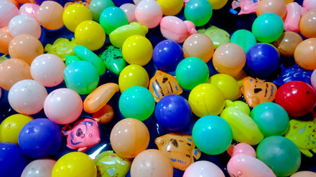 An overhead image of floating plastic balls and toy fish in a pool of water, commonly used in...