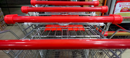 A close-up, eye-level view of a stack of supermarket shopping carts, with their distinctive red...