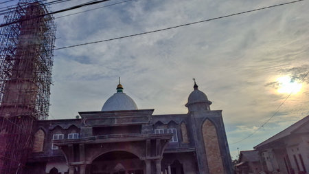 Mosque dome and minaret construction under sunset skyの写真素材