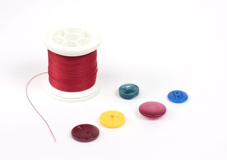 bright red thread and scattered colored buttonsの写真素材