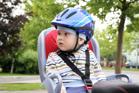 child sitting by bicycle in crash helmet