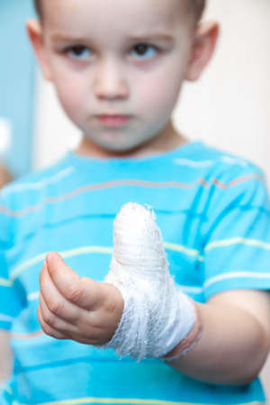 wounded in the left hand with bandage boy at shot in homeの写真素材