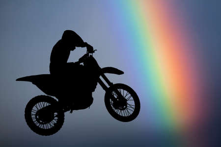 Motocross - silhouette with colorful rainbow in the skyの写真素材