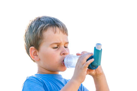 Boy using inhaler for asthma in village with summer sunsetの写真素材